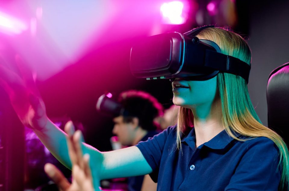 blond-girl-in-vr-goggle-touching-virtual-display-d-2023-11-27-05-25-15-utc-960x636